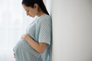 Pregnant Caucasian woman holding her belly in hospital