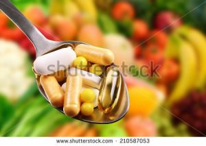 stock-photo-spoon-with-dietary-supplements-on-fruits-background-210587053